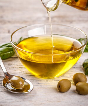 Bottle pouring virgin olive oil in a bowl close up
